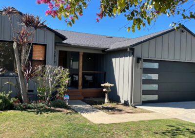 Modern ranch home with contemporary black garage door, grey siding, and Japanese-inspired landscaping.